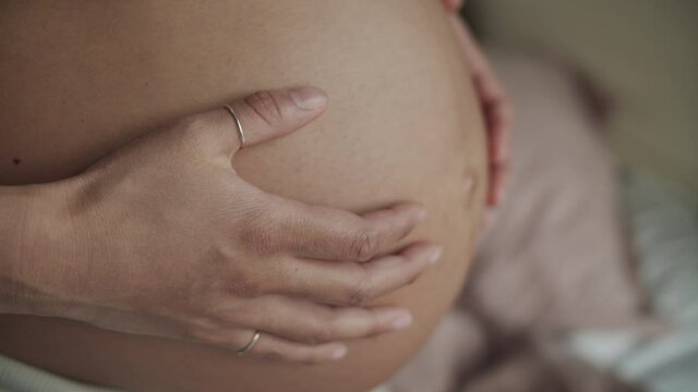 Close up shot showing pregnant woman Caressing her Pregnant Belly.