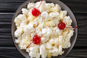 American dessert salad consisting of rice, marshmallows and pineapple dressed with whipped cream close-up in a plate on the table. horizontal top view from above