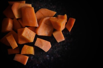 Fresh carrots on a wooden kitchen board with a black background.