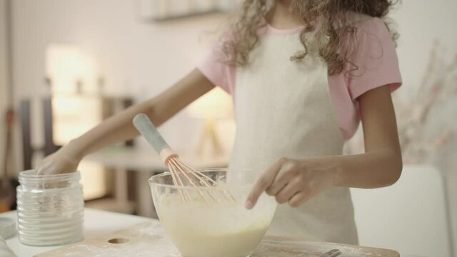 Teen girl adding ingredients to bowl, cooking pastry at baking workshop, hobby