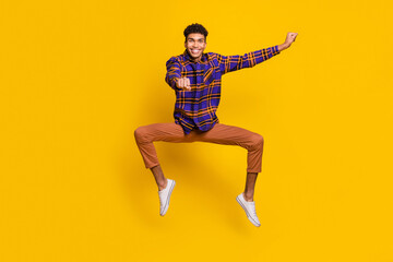 Fototapeta na wymiar Full length photo of carefree handsome dark skin man jumping ride imagine horse isolated on yellow color background