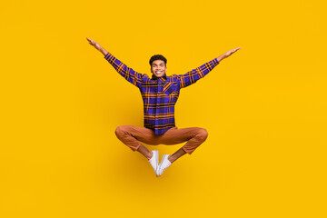 Full length body size photo of young man smiling childish careless jumping up isolated vibrant...