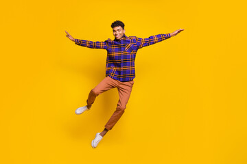 Full length body size photo of young man smiling carefree playful jumping up isolated vivid yellow...