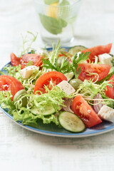 Salad with Green Olives, Tomatoes and Feta Cheese. Bright wooden background. Close up.