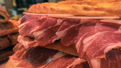 Fresh sandwich made with bread and slices of spanish iberian ham (in spanish Jamón iberico). Spanish ham baguette sandwiches on display for sale in Valencia