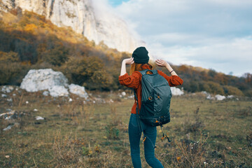 a traveler in a sweater with a backpack on her back warm hat landscape autumn mountains