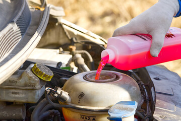 Pouring coolant, Service of cars. Pouring antifreeze. Mechanic fills the coolant G12 to tank in the...