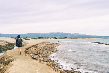 girl strolling on the shore of the beach on a cloudy day
