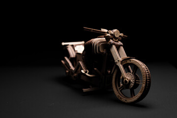 Fototapeta na wymiar Toy motorcycle made of plywood on a black background