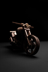 Wooden toy motorcycle on a black background a close up