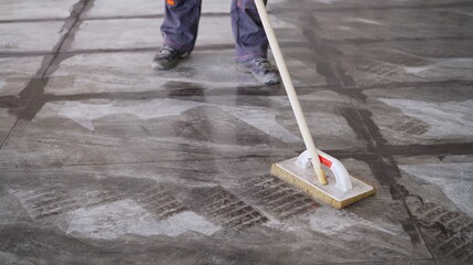 Worker washing tiles after work. A worker washes the tiles on the floor after grouting.
