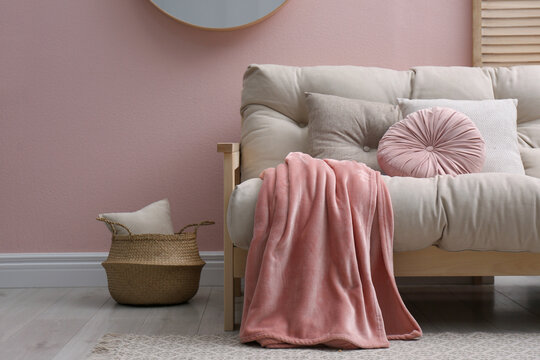 Modern living room interior with comfortable sofa and pink blanket
