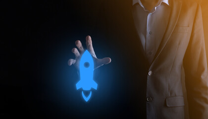 Startup business concept, Businessman holding tablet and icon rocket is launching and soar flying out from screen with network connection on dark background.