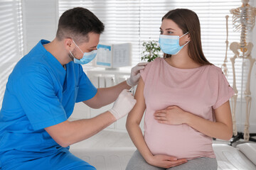 Doctor vaccinating pregnant woman against Covid-19 in clinic