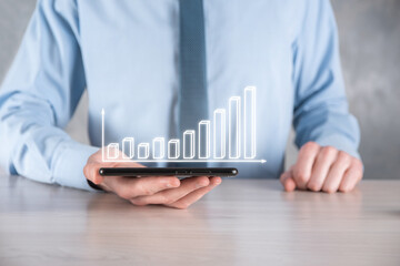 Businessman man holding a graph with positive profits growth. plan graph growth and increase of chart positive indicators in his business.more profitable and growing