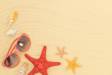 Summer beach background with sand, starfishes, sunglasses, seashells