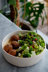 Vegan bowl with chickpea falafel balls and salad. Clean eating concept. Cruelty free fast food restaurant table with plate full of food. Close up, copy space, background.