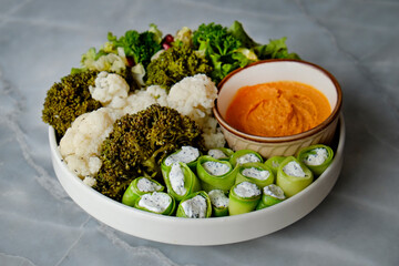 Vegan plate with zucchini rolls, hummus, mixed salad leaves, herbs and greens. Clean eating concept. Cruelty free fast food restaurant table with plate full of food. Close up, copy space, background.