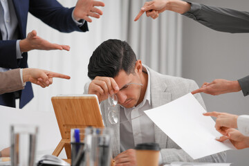 Coworkers bullying their colleague at workplace in office, closeup