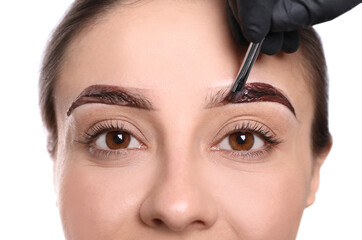 Beautician applying tint during eyebrows correction procedure on white background, closeup