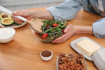 Woman with salad at wooden table, closeup. Keto diet