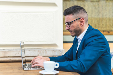 Businessman Using Laptop While Drinking Coffee in a Cafe.