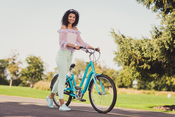 Full size photo of optimistic brunette lady stand bicycle wear lilac top pants sneakers outside in park