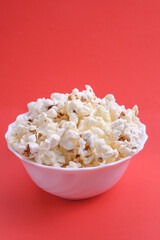 Popcorn in bowl on a red background. Close up. Top view