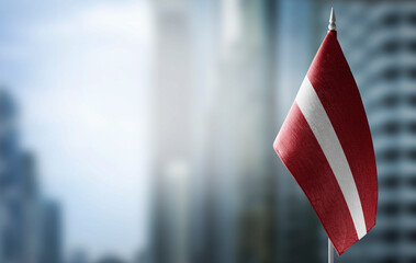 A small flag of Latvia on the background of a blurred background