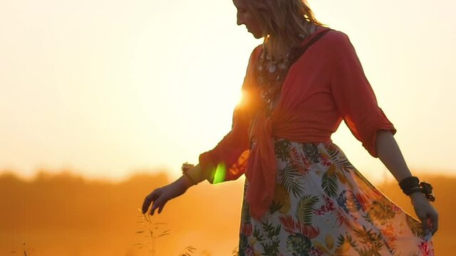 Attractive woman aged boho style.Portrait of blonde hippie in a field on a background of sunset. Woman in boho style on the background of a field and sunset.