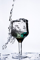 Stream of water, splashes and drops from a wine glass on a light background. Selective focus