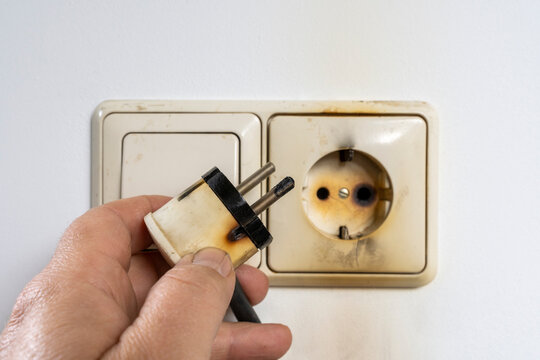 Burned eu style socket in hand. Power Plug after short circuit and fires on white background