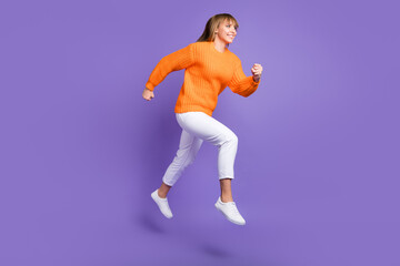 Obraz na płótnie Canvas Profile photo of lady jump run fast wear orange sweater trousers footwear isolated violet color background