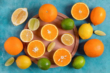 Close-up top view of ripe citrus fruits whole and cut on a round wooden cutting board. Selective focus.