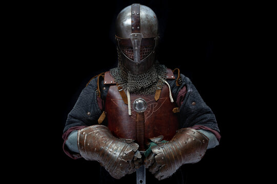 Young man in knight armor on black background