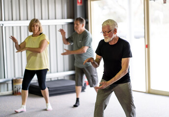Group of elderly senior people practicing Tai chi class in age care gym facilities.