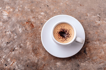 Single cup of coffee with cream and chocolate chips on a beautiful textured gray background with orange streaks