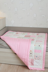 Cozy baby cot with pink patchwork blanket. Baby bedding. Bedding and textile for nursery. Nap and sleep time