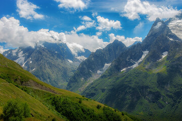Fototapeta na wymiar Spring, mountains and peaks covered with green grass and remnants of snow in Dombai, Caucasus