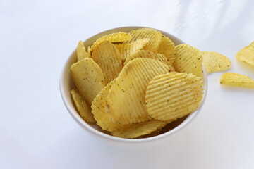 Potato chips in a bowl on white table background. Top view, copy space	