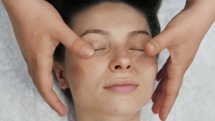 Beautiful young girl doing face and head massage in spa salon. Relax.