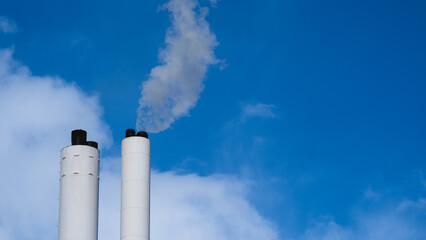 Smoke from chimney set against a blue sky