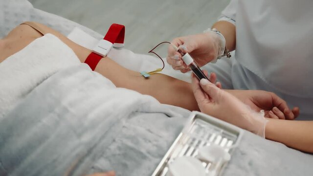 Nurse taking a blood sample from a patient lying in a hospital ward. Blood collection from a sick person in a hospital in a cell.