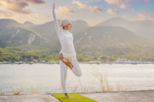 Kundalini yoga woman in white clothes and turban practices yoga kundalini on the background of the sea, mountains and sunset. Fighting face painting of the Indians shows her inner world. Visual