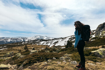 young woman standing looking at mountain landscape. Snowy mountains