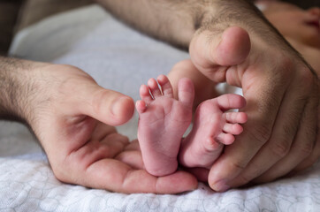 Un padre envuelve con sus manos los pies de su hijo recien nacido