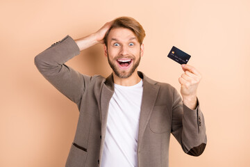Photo of impressed nice blond hair man hold card wear grey jacket isolated on beige background
