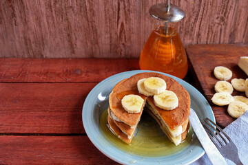 Home-made banana pancake on a blue plate. Eat with maple syrup or honey and fresh fruit. The concept of healthy homemade food. Copy space