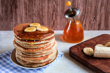 Pancakes with banana,walnut and muple syrup for a breakfast on wooden background closeup.