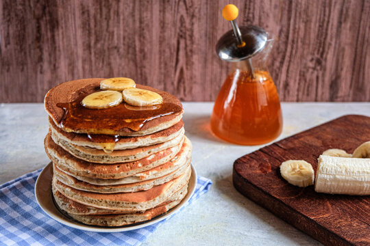 Pancakes with banana,walnut and muple syrup for a breakfast on wooden background closeup.